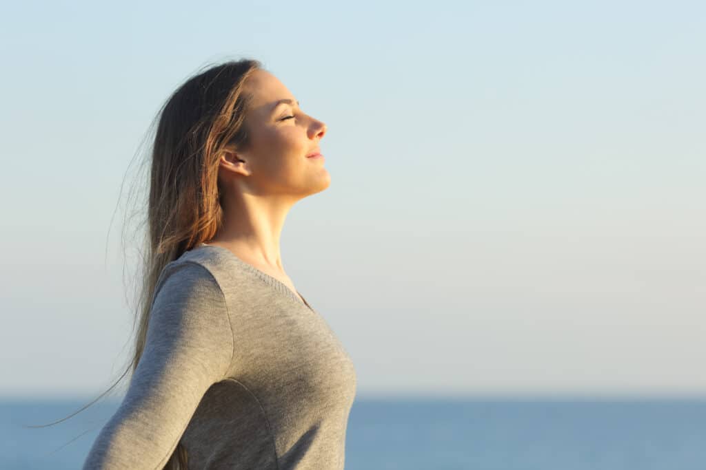 Side view portrait of a relaxed woman breathing fresh air on the beach