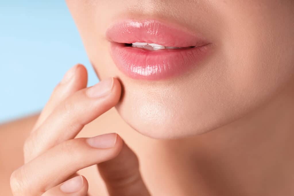 Woman with beautiful lips on light blue background, macro view